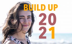 a smiling woman on a beach with the words Build Up 2021